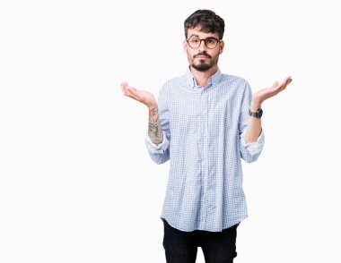 İzole arka plan clueless ve şaşkın bir ifadeyle kollar ve eller kaldırdı üzerinde gözlük takan yakışıklı delikanlı. Şüphe kavramı.