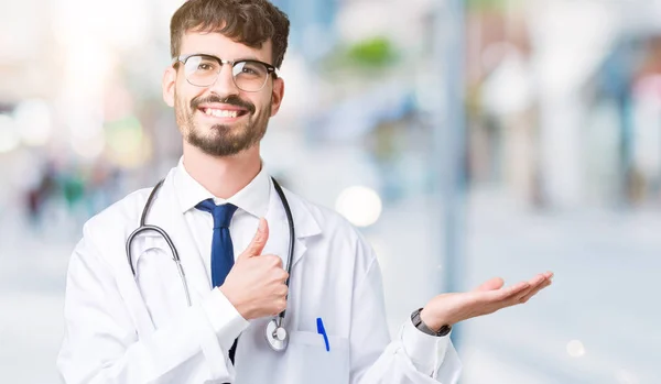 Junger Arzt Trägt Krankenhausmantel Über Isoliertem Hintergrund Zeigt Handfläche Und — Stockfoto
