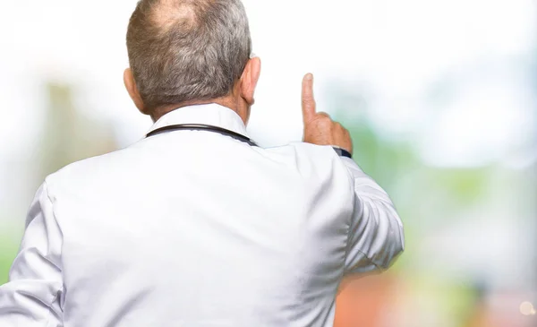 Handsome Senior Läkare Man Bär Medicinsk Päls Posing Bakåt Pekar — Stockfoto