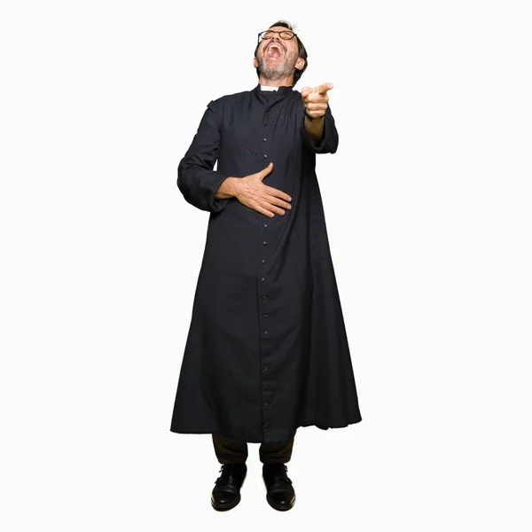 中年牧师男子穿着天主教长袍笑你 指着相机用手指手在胸部 羞愧的表情 — 图库照片