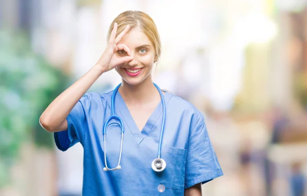 幸せそうな顔で指を通して見る目の手で のジェスチャーを行う分離の背景に美しい金髪女医外科医看護師女性 — ストック写真