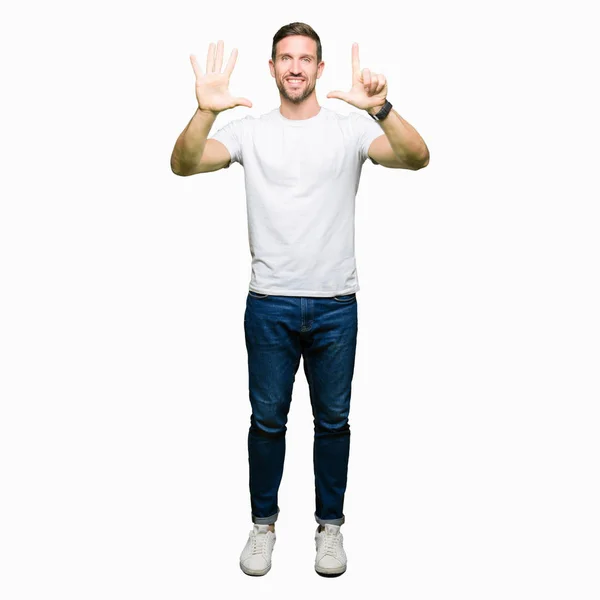 ハンサムな男の指で上向きの表示とカジュアルな白の シャツを着て数は自信を持って 幸せな笑みを浮かべている間 — ストック写真
