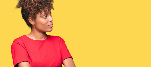 Beautiful young african american woman over isolated background smiling looking to the side with arms crossed convinced and confident