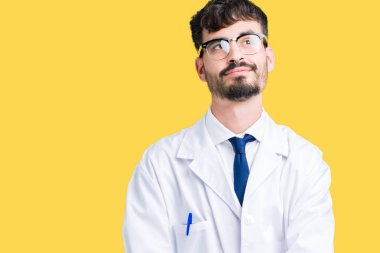 Görünümlü yan ve dik dik bakma uzağa düşünce gülümseyen izole arka plan üzerinde beyaz önlük giyen genç profesyonel bilim adam.