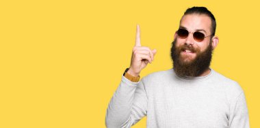 Genç hipster adam başarılı fikirle parmak işaret güneş gözlüğü takıyor. Çıktıktan ve mutlu. Bir numara.