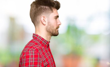 Yandan bakan yakışıklı bir genç, rahat profil pozu, doğal bir yüz ve kendine güvenen bir gülümseme..