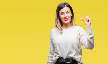 Genç güzel kadın rahat beyaz kazak izole arka plan gülümseyen ve boyutu işaret parmaklı ararken ve kamera işi el ile kendinden emin eller üzerinde. Ölçü kavramı.