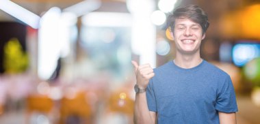 Hareketi el ile mutlu yaşasın yapıyor izole arka plan üzerinde mavi t-shirt giyen genç yakışıklı adam. Başarı gösteren kameraya bakarak ifade onaylama.