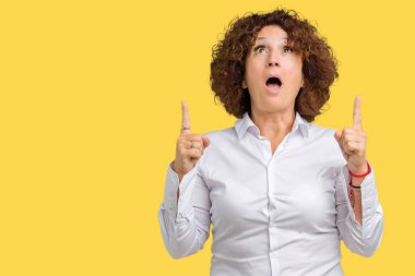 Güzel orta ager üst düzey businees kadın izole arka plan üzerinden hayran ve yukarıya bakıp parmakları ile işaret şaşırttı ve silah kaldırdı.