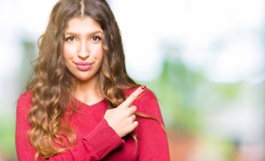 Kırmızı kazak giyen genç güzel kadın el parmak ile gösterilen reklam, ciddi ve sakin yüz tarafına işaret