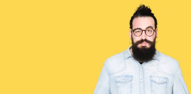 Uzun saç ve sakal komik surat ile yanakları şişirme gözlüklü genç hipster adam. Ağız ile hava, deli ifade şişirilmiş.