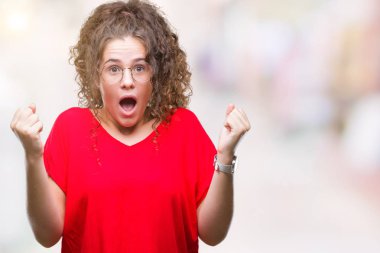 Güzel esmer kıvırcık saçlı Genç kız izole arka plan üzerinde kutluyor gözlük takan şaşırttı ve silah ile başarı için hayran kaldırdı ve gözleri açık. Kazanan kavramı.