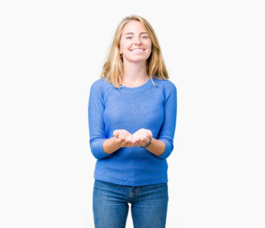 Mavi kazak izole üzerinde giyen güzel genç kadın alma veya jest vererek birlikte el avuç içi ile gülen arka plan. Ayrı tutma ve koruma