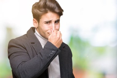 İzole arka plan kokulu üzerinde kış ceket pis ve iğrenç bir şey, dayanılmaz koku, holding nefes parmak ile burun üzerinde giyen genç zarif adam. Kötü kokuyor kavramı.