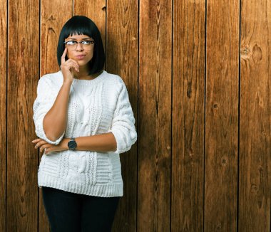 Güzel genç Afro-Amerikan kadın gözlük ile izole arka plan üzerinde çene düşünme hakkında soru, dalgın ifade ver. Düşünceli yüzüyle gülümsüyor. Şüphe kavramı.