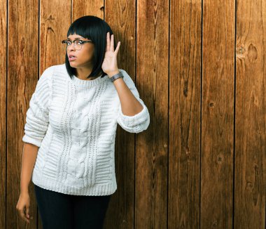 Gözlüklü bir işitme söylenti ya da dedikodu için dinleme kulak üzerinde el ile gülümseyen izole arka plan üzerinde güzel genç Afro-Amerikan kadın. Sağırlık kavramı.