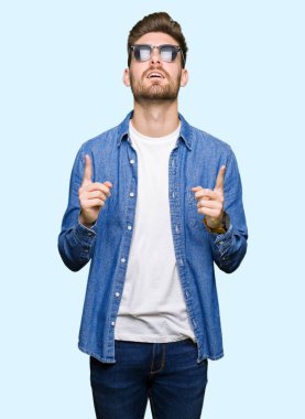 Kot ceket giyen genç yakışıklı zarif adam hayran ve bakmak ve parmaklar ve yükseltilmiş kollar ile işaret şaşırttı.