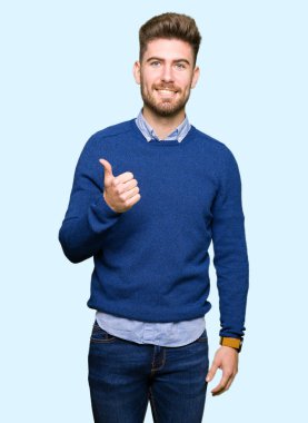 Genç yakışıklı Bussines adam yapıyor mutlu thumbs yukarı jest ile el. Başarı gösteren kameraya bakarak ifadeyi onaylama.