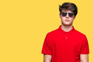 Genç yakışıklı adam yüzünde ciddi bir ifade ile izole arka plan üzerinde güneş gözlüğü takıyor. Basit ve doğal kameraya bakıyor.