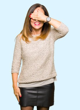 Moda kazak gülümseyen ve gözler için sürpriz kapsayan yüz el ile gülüyor giyen güzel orta yaş kadın. Kör kavramı.