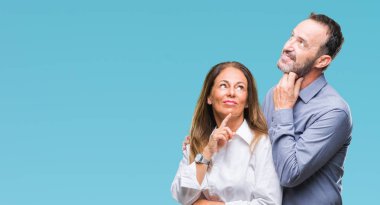 Orta yaş İspanyol iş çift ile izole arka plan üzerinde çene düşünme hakkında soru, dalgın ifade ver. Düşünceli yüzüyle gülümsüyor. Şüphe kavramı.