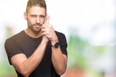 El hareketi ile sembolik silah tutan, çekim silah, kızgın yüz öldürmek oynamaya izole arka plan üzerinde genç yakışıklı adam