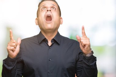 İzole arka plan üzerinde yakışıklı orta yaş Arap iş adamı şaşırdı ve görünümlü ve parmaklar ve yükseltilmiş silah ile işaret şaşırttı.