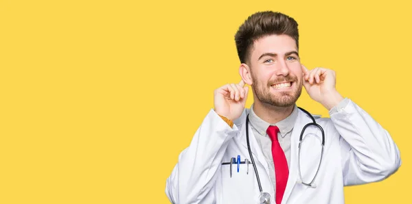 Young Handsome Doctor Man Wearing Medical Coat Smiling Pulling Ears — Stock Photo, Image