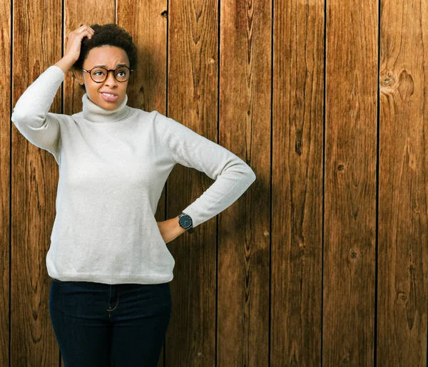 Young beautiful african american woman wearing glasses over isolated background confuse and wonder about question. Uncertain with doubt, thinking with hand on head. Pensive concept.