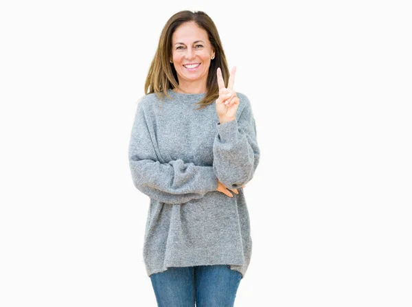 幸せな顔をして笑っている孤立した背景の上に冬のセーターを着た美しい中年の女性勝利のサインをしているカメラでウィンク — ストック写真