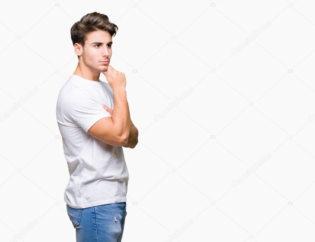 Young handsome man wearing white t-shirt over isolated background with hand on chin thinking about question, pensive expression. Smiling with thoughtful face. Doubt concept.