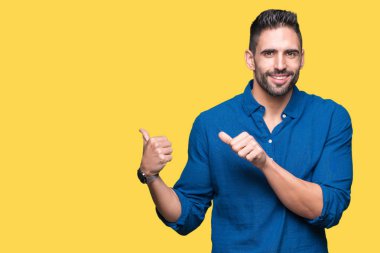 Yakışıklı delikanlı izole arka plan üzerinde emin gülümseyen arkasından el ve kadar başparmak ile işaret
