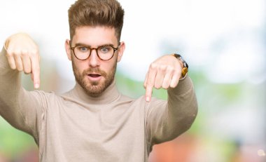 Gözlük takan genç yakışıklı iş adamı parmak gösteren reklam, sürpriz yüz ve açık ağız ile aşağı Işaret