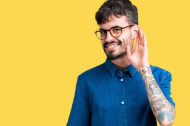 Bir işitme söylenti ya da dedikodu için dinleme kulak üzerinde el ile gülümseyen izole arka plan üzerinde gözlük takan yakışıklı delikanlı. Sağırlık kavramı.