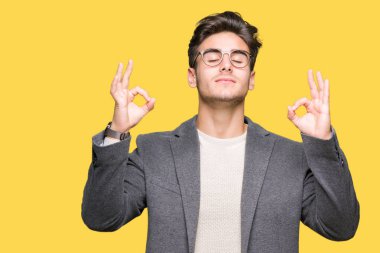 Genç iş adamı gözlük izole arka plan üzerinde dinlenmek ve gülümseyen gözlerle kapalı parmak jestle meditasyon yapıyor. Yoga kavramı.