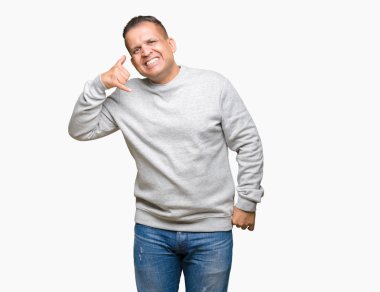Orta yaş Arap adam üzerinde spor sweatshirt giyen izole arka plan üzerinde telefonda konuşmak gibi el ve parmaklar ile telefon jest yapıyor gülümseyen. İletişim kavramları.