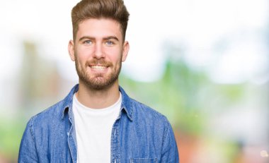 Yüzünde mutlu ve güzel bir gülümseme ile rahat denim ceket giyen genç yakışıklı sarışın adam. Şanslı kişi.