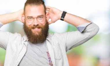 Genç Sarışın adamın giydiğini dinlenirken ve kollarını açarak germe gözlük ve baş ve boyun, mutlu gülümseyerek eller