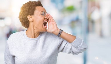 Bağırarak ve ağzı üzerinde el ile yan için çığlık izole arka plan üzerinde gözlük takan genç güzel Afrikalı-Amerikalı kadın. İletişim kavramı.