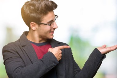 Genç yakışıklı zarif adam gözlüklü üzerinden hayran ve el ile sunulması ve parmak ile işaret ederken kameraya gülümseyen izole arka plan.