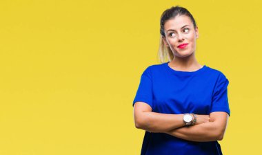 Görünümlü yan ve dik dik bakma uzağa düşünce gülümseyen izole arka plan üzerinde rahat mavi t-shirt giyen genç güzel kadın.