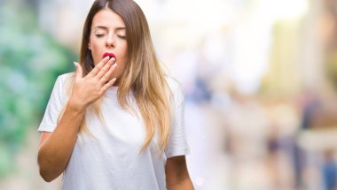 Genç güzel kadın esneme Casual beyaz t-shirt izole arka plan üzerine sıkılmış kapsayan ağız el ile yorgun. Restless ve uyku hali.