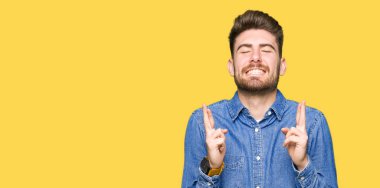 Genç yakışıklı sarışın adam geçiş parmakları umut ve gözler gülümseyen rahat kot gömlek giymiş kapalı. Şans ve batıl kavramı.