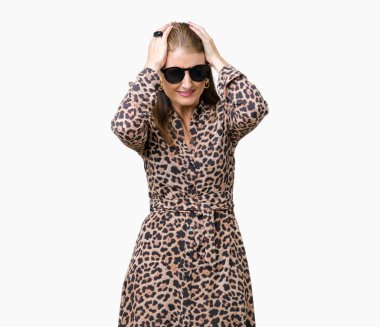 Üzerinde güneş gözlüğü ve leopar elbise giyen orta yaş olgun zengin kadın izole çünkü umutsuz ve stresli baş ağrısı acı arka plan ağrı ve migren. Ellerini kafasına.