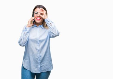 Genç güzel iş kadın konuşma arama Smartphone ile mutlu yüz el parmaklarının arasından seyir göz üzerinde ok işaretiyle yapıyor gülümseyen izole arka plan üzerinde kullanma