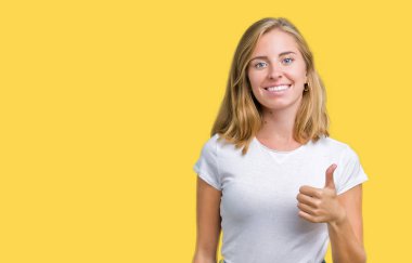 Hareketi el ile mutlu Yaşasın yapıyor izole arka plan üzerinde rahat beyaz t-shirt giyen güzel ve genç birbayan. Başarı gösteren kameraya bakarak ifade onaylama.