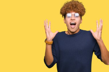 Yakışıklı delikanlı ile deli kutluyor gözlük takan ve silah ile başarı için heyecanlı çığlık kaldırdı ve açık gözleri hayret afro. Kazanan kavramı