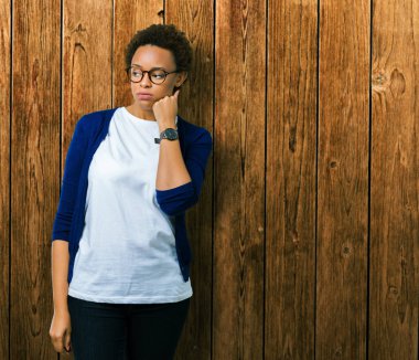 Genç güzel Afrikalı-Amerikalı kadın seyir yorgun ve bıkkın ile depresyon sorun Çapraz kollar ile izole arka plan düşünme üzerinde gözlük.