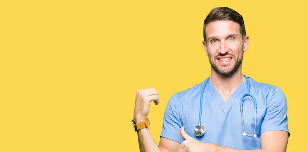身に着けている医療制服上分離されたハンサムな医者男背景自信の笑みを浮かべて手と親指 裏側を指す — ストック写真