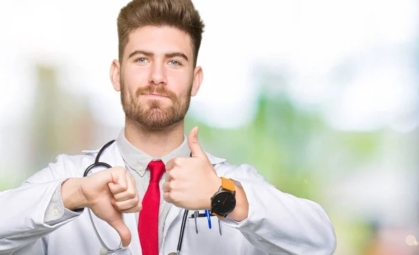 Joven Doctor Guapo Con Abrigo Médico Haciendo Pulgares Arriba Abajo — Foto de Stock